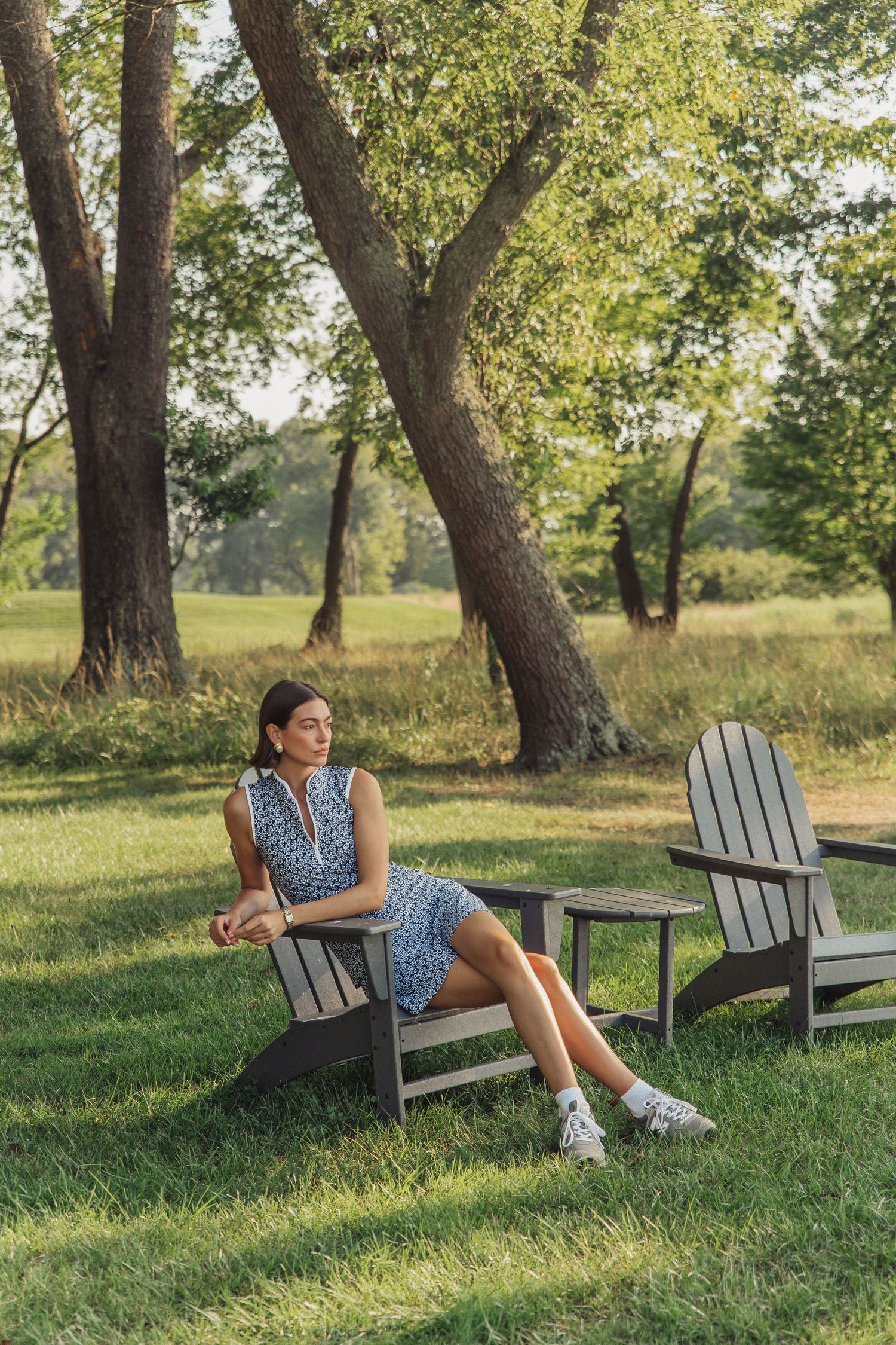 Model Haylee Michalski sitting in Adirondack chair at Queenstown Harbor Golf Resort, golf fashion photography for Smith & Quinn