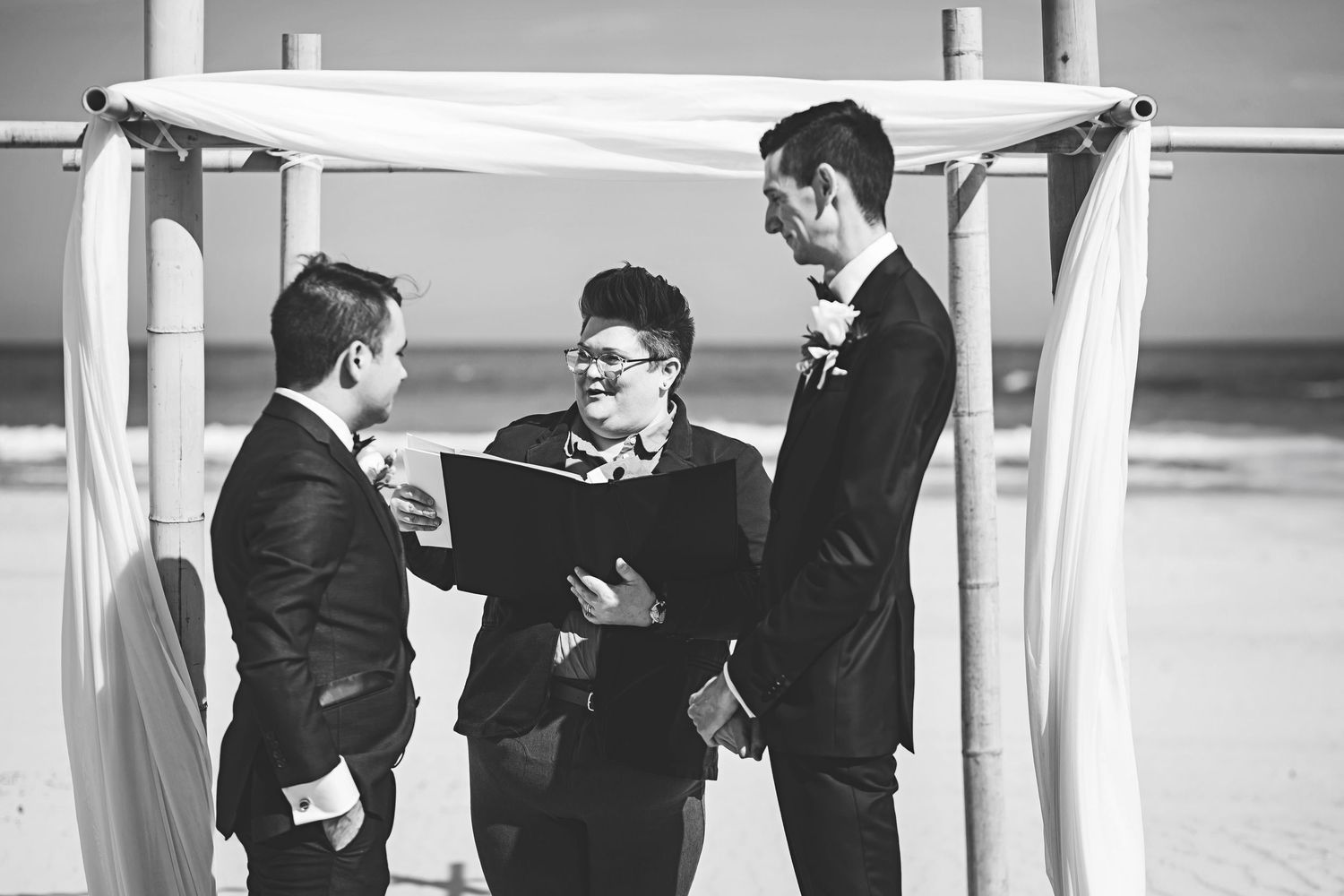 Professional businessmen in suits having a conversation in a bright office hallway.
