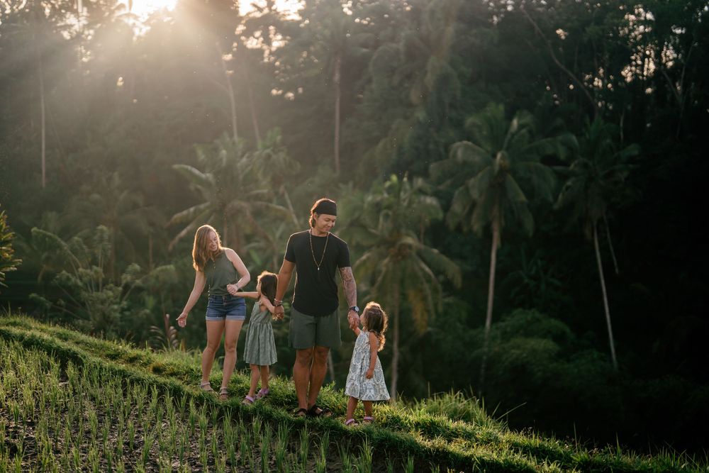 Family walking together along terraced rice fields at golden hour.
