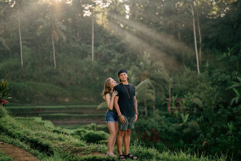 Couple standing together on terraced hillside during sunset.