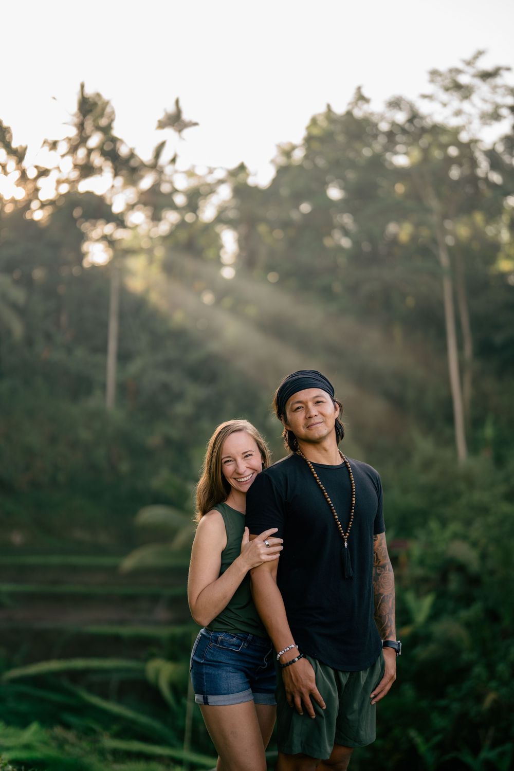 Couple poses together on tropical terraced hillside during golden hour.