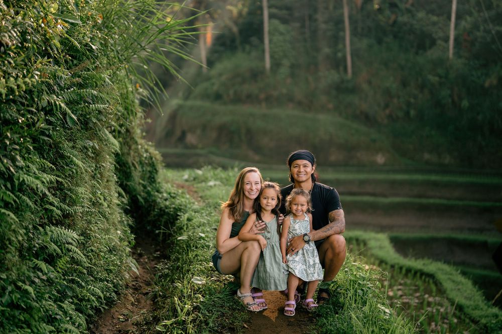 Family group poses together on green terraced rice field path.