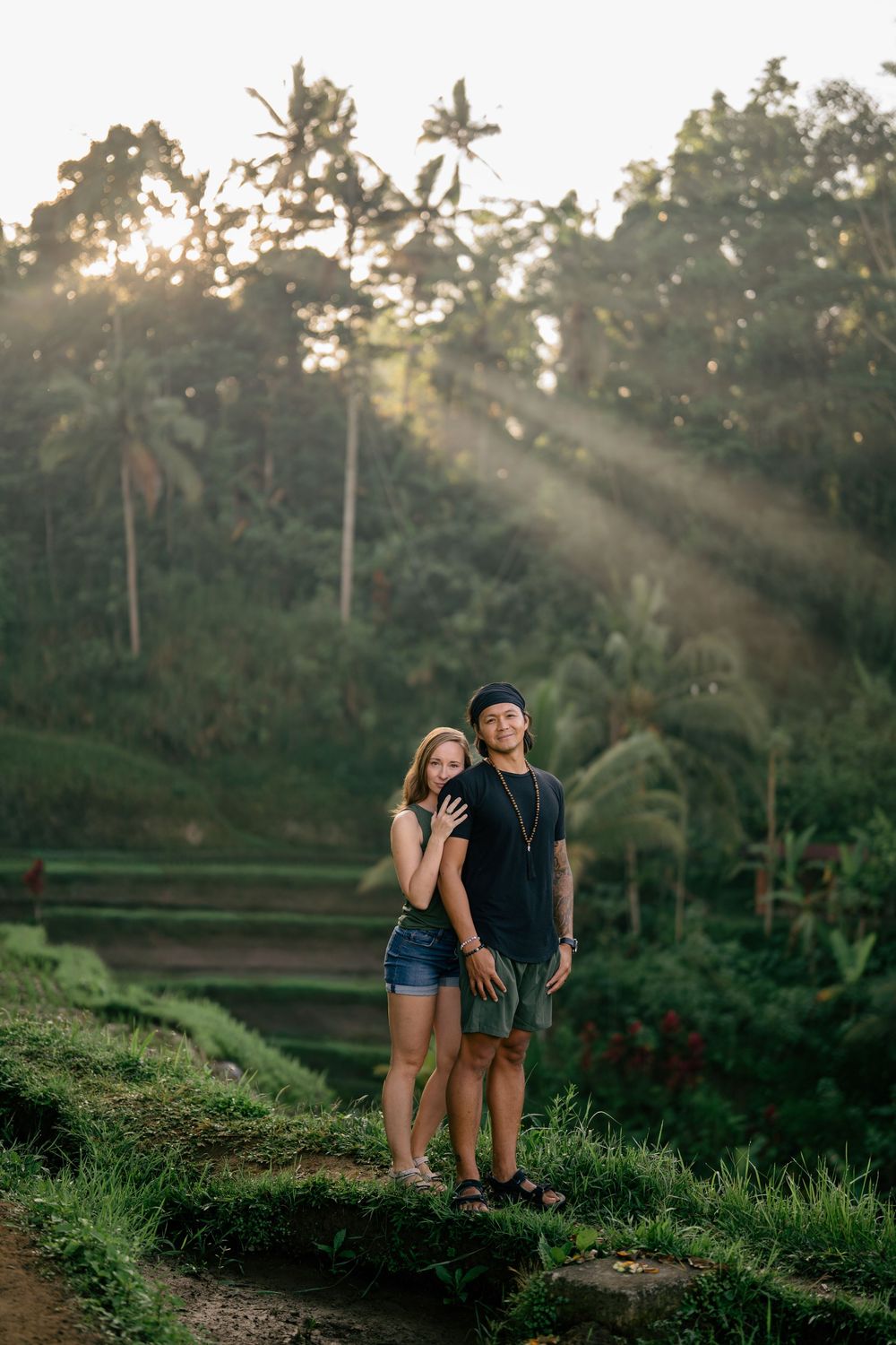 Couple enjoying sunset view over terraced rice fields with palm trees in background.
