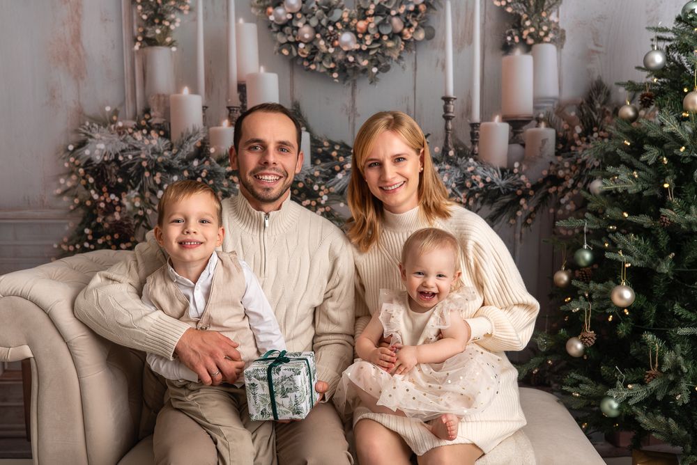 mum, dad and brother and sister, family of 4, sitting together on the sofa, smiling, Christmas tree