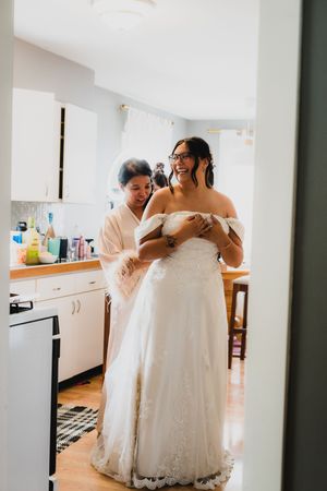 Emotional wedding day moments shared in a bright kitchen as the bride gets ready in her white lace gown.