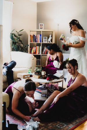 Wedding party preparations in a casual home setting with books and decor visible.