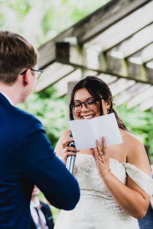 Couple shares a joyful moment reading letters to each other in an outdoor setting.