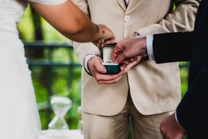 Close-up details of formal attire and hands during wedding ceremony.