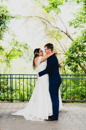 A romantic first kiss moment between newlyweds on a stone terrace surrounded by greenery.