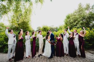 Wedding party poses for group photos outdoors wearing burgundy and neutral colors.