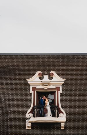 A creative wedding photo series showing couples in decorative white window frames against a dark brick wall.