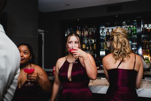 A group of people enjoying drinks and socializing at a dimly lit bar counter.
