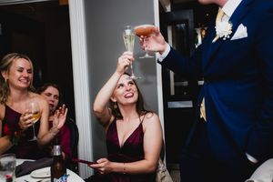People enjoying drinks and toasting with glasses at a formal event in dark attire.