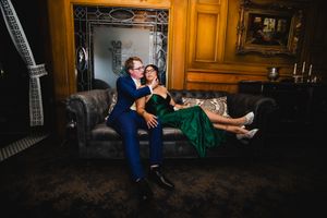 A couple in formal attire share an intimate moment in an elegant room with ornate wood paneling and warm lighting.