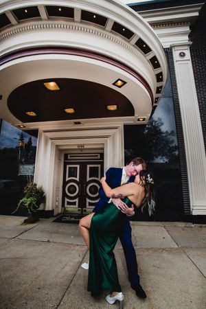 Romantic dip pose under elegant white archway entrance during sunset.