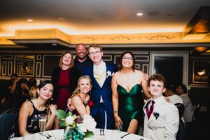 Wedding reception guests gather at a venue with warm ambient lighting and elegant decor.