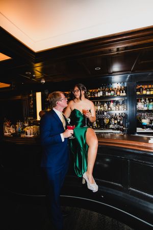 Romantic moment at an elegant dark bar with mood lighting and bottles displayed on shelves.