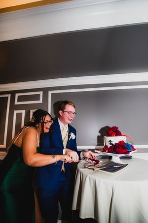 Wedding guests lean over a table in a row while checking their phones in a coordinated pose.