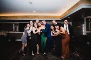 Wedding guests dancing and celebrating together in a dimly lit reception hall.