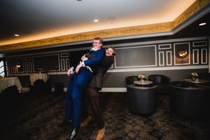 A couple dances together in an elegant dark ballroom with decorative wall paneling and ambient lighting.