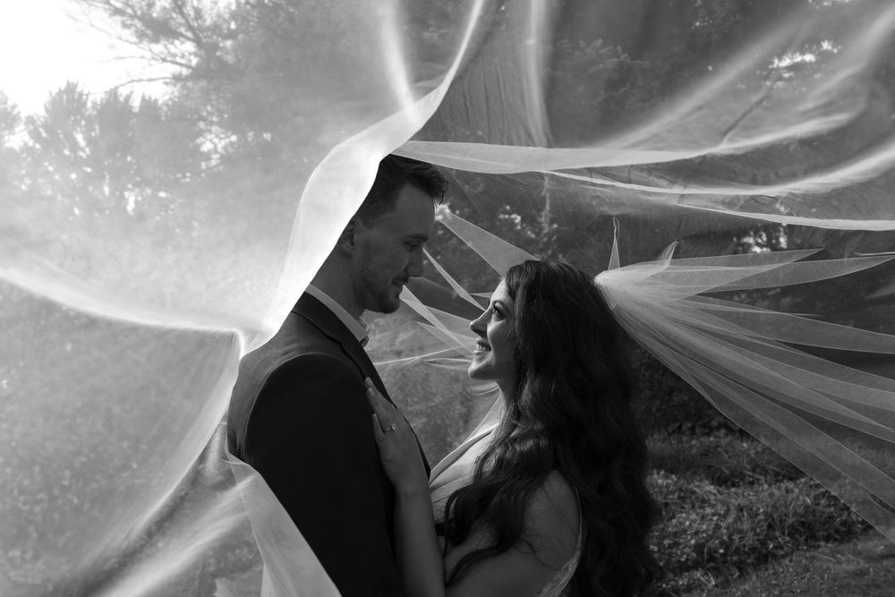 A black and white artistic wedding photo series showing flowing veil movement against a dreamy outdoor background.