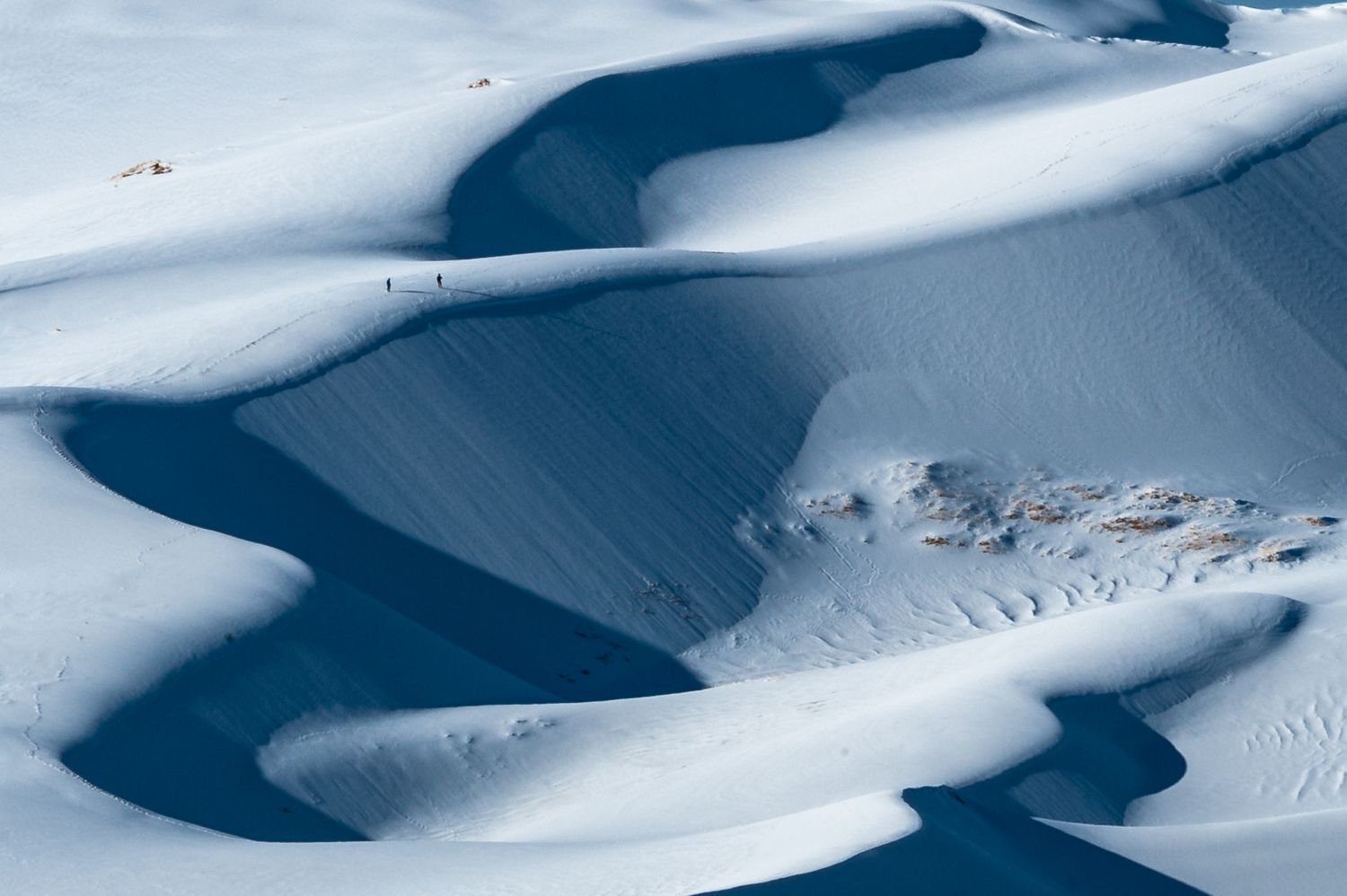Aerial view of snow-covered mountain slopes creating dramatic curves and patterns in winter landscape.