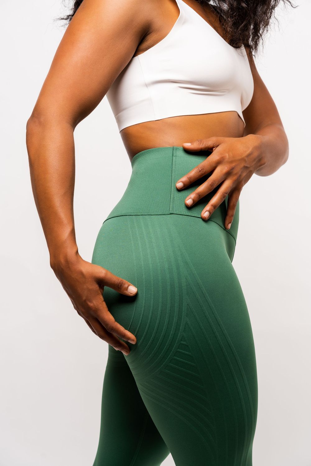 Close-up views of athletic leggings in forest green color shown from different angles on a white background.