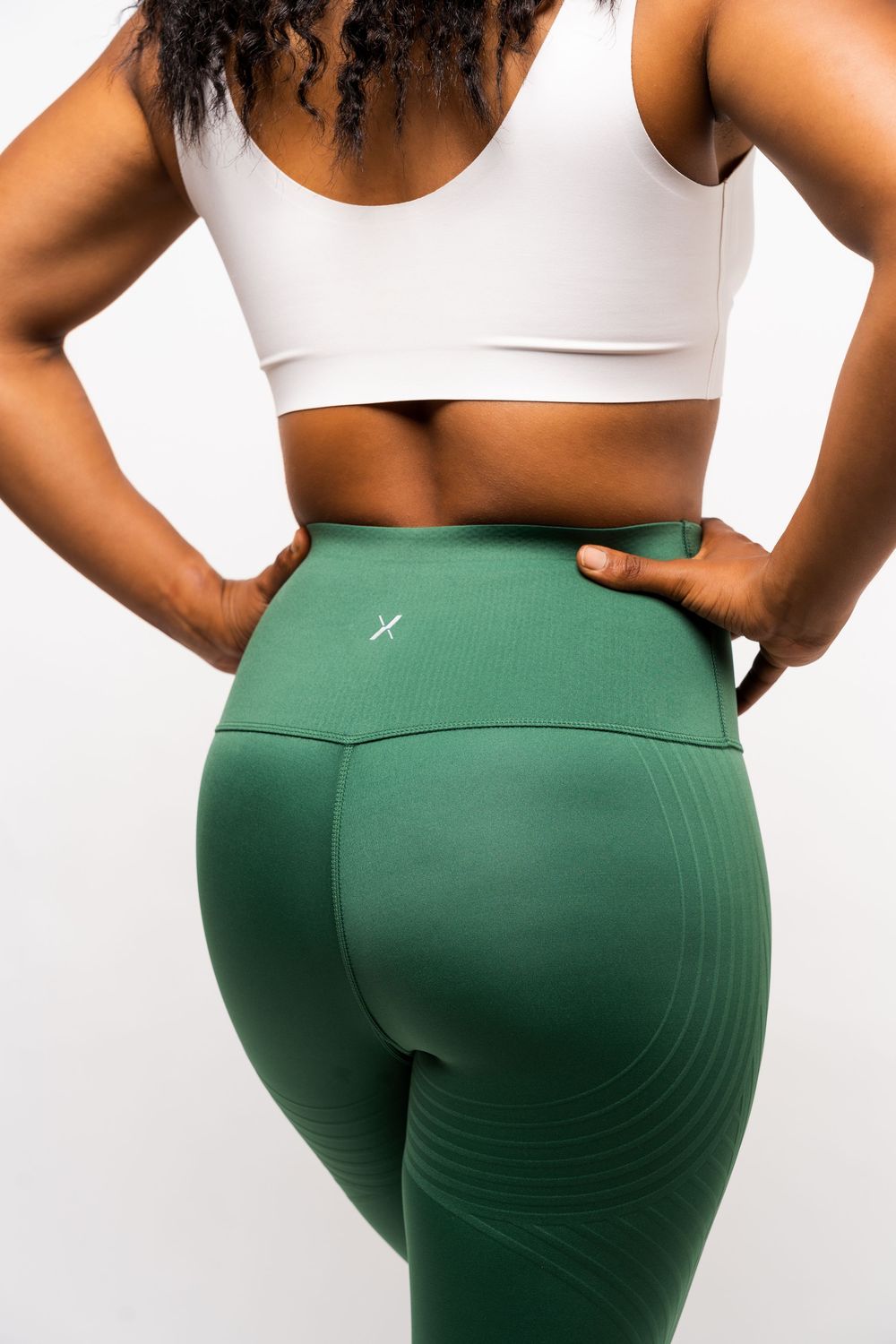 Close-up view of athletic wear featuring a white sports bra and green high-waisted leggings with seamless pattern details.
