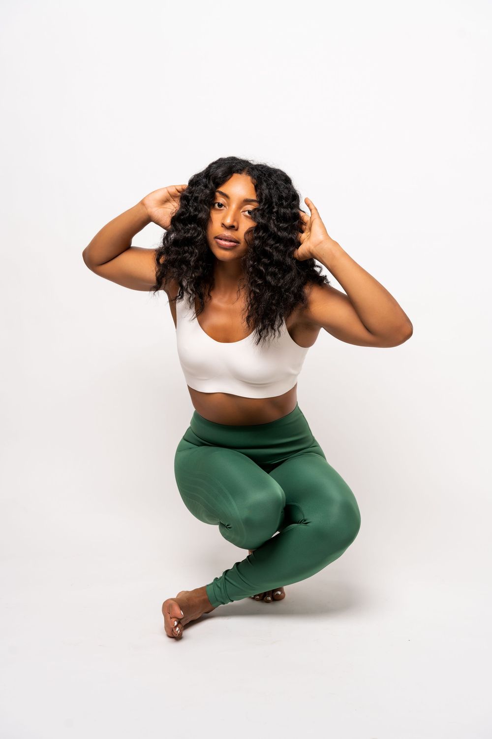 Athletic woman in white sports bra and green leggings strikes dynamic yoga poses against white background.