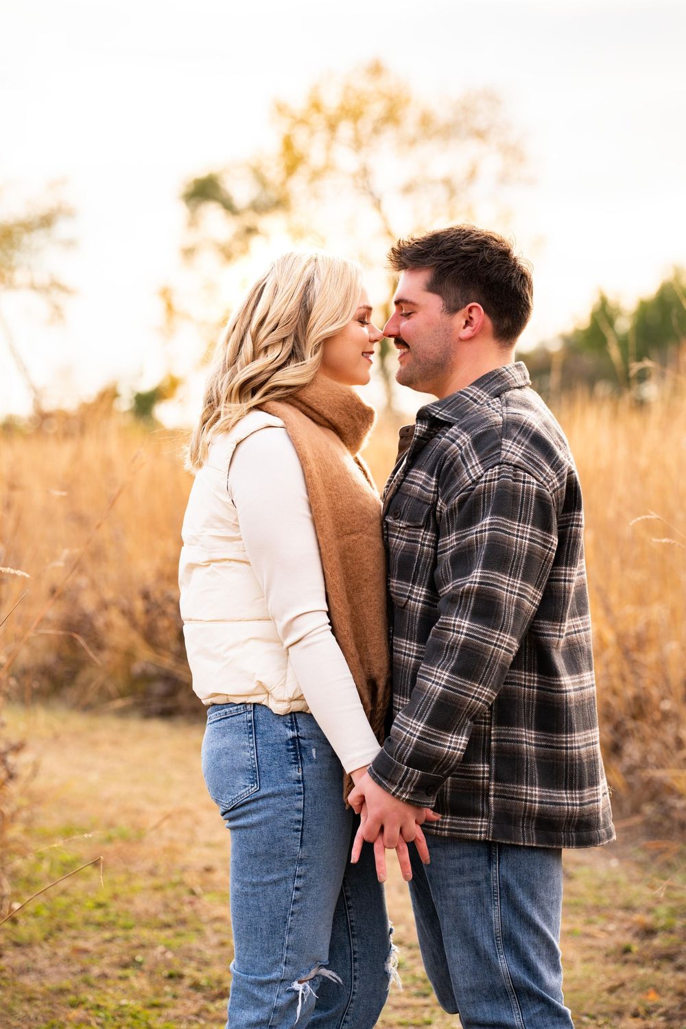 A couple shares an intimate moment in a golden field at sunset.