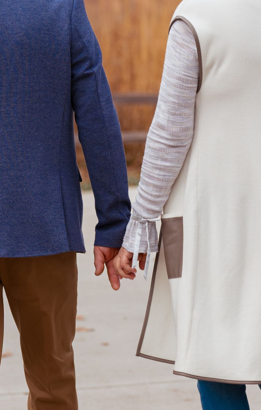 Close-up shot of two people holding hands while walking together.
