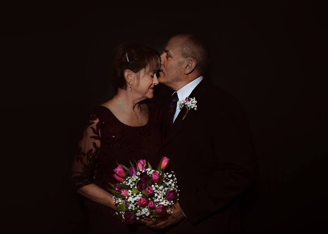 Couple holding bouquet in dark room celebrating vow renewal in Springfield Missouri.