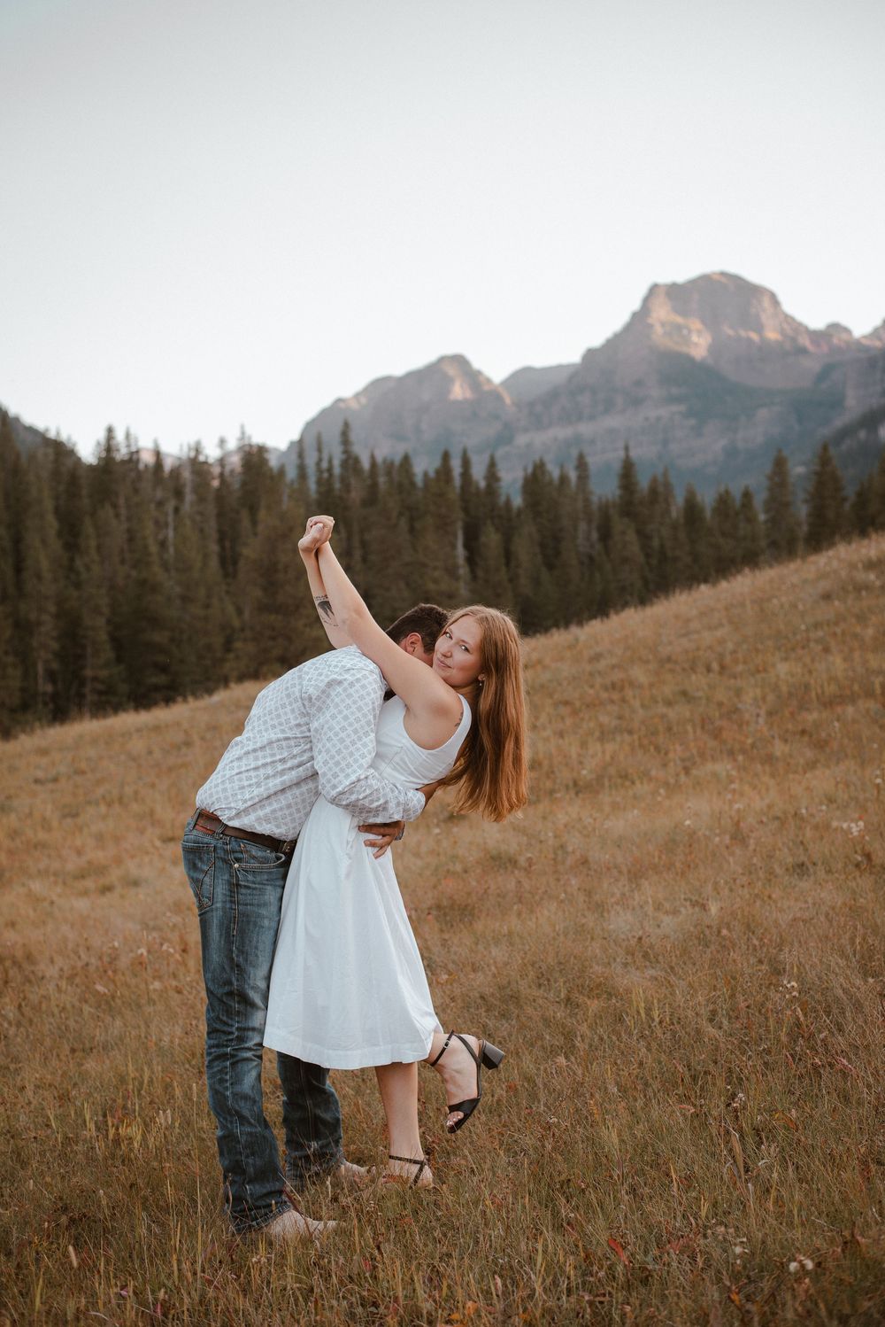 A playful dance sequence in a mountain field with dramatic rocky peaks in the background.