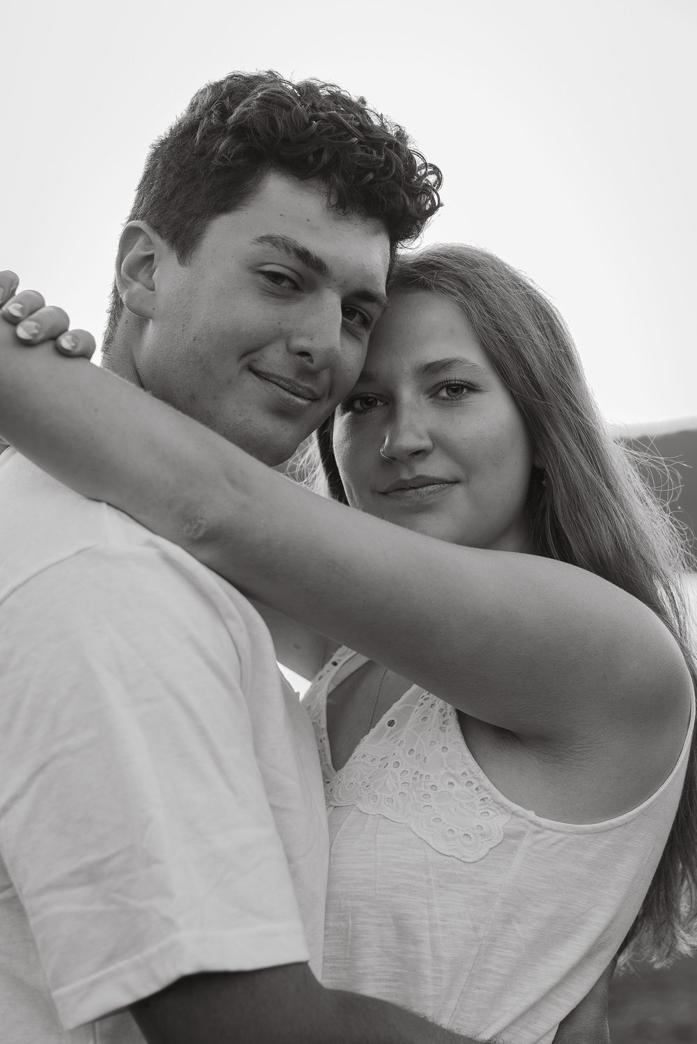 A romantic black and white photo series showing a couple embracing in casual white outfits.