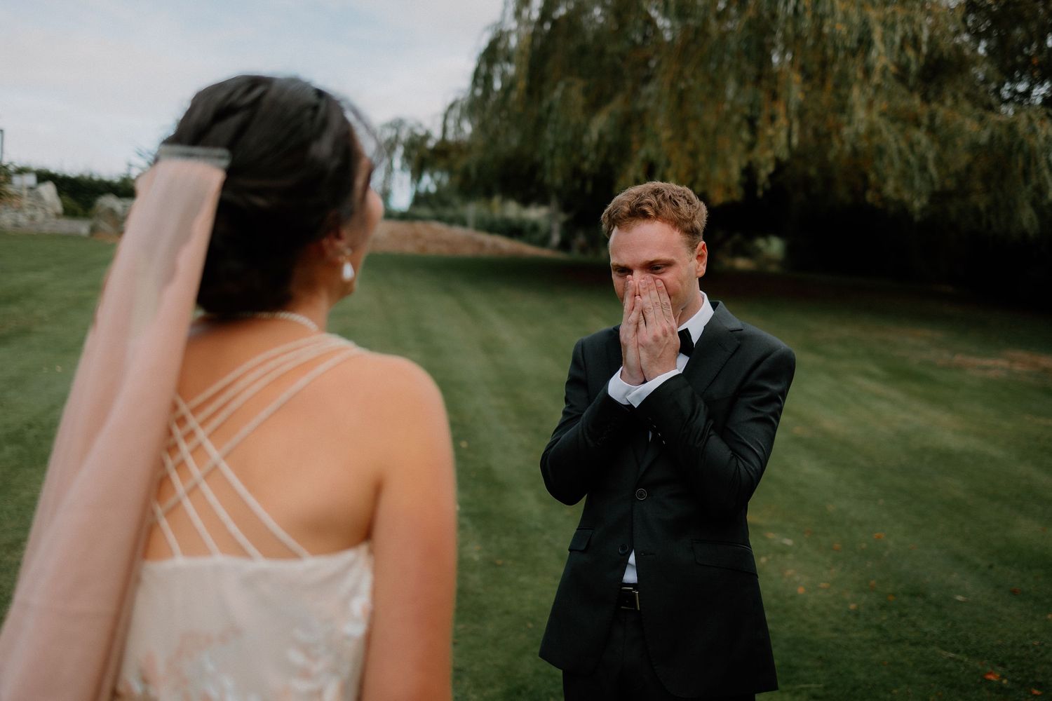 A tender black and white wedding photo moment between a bride in a white gown and another person outdoors.