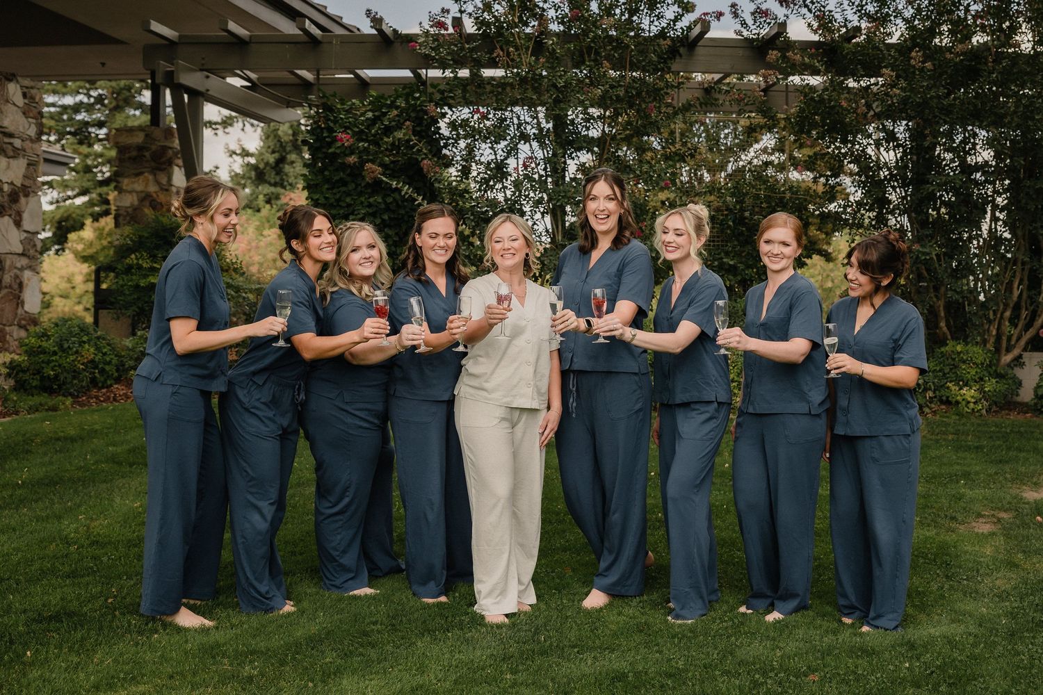 Group photo of wedding party members wearing navy blue attire posing together outdoors.