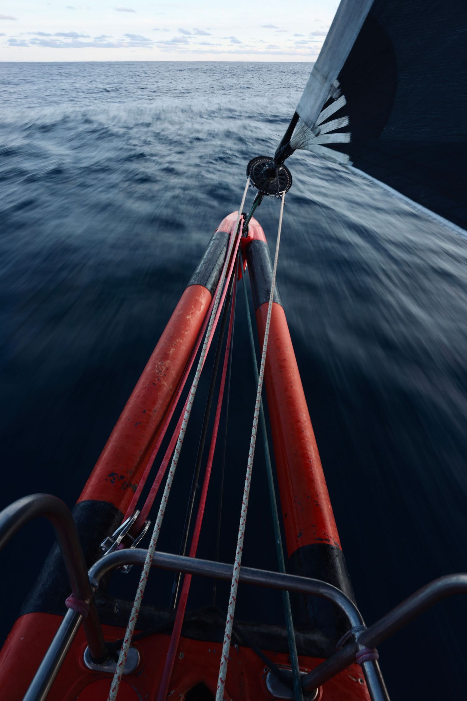 Red safety equipment mounted on sailing vessel with ocean in background.