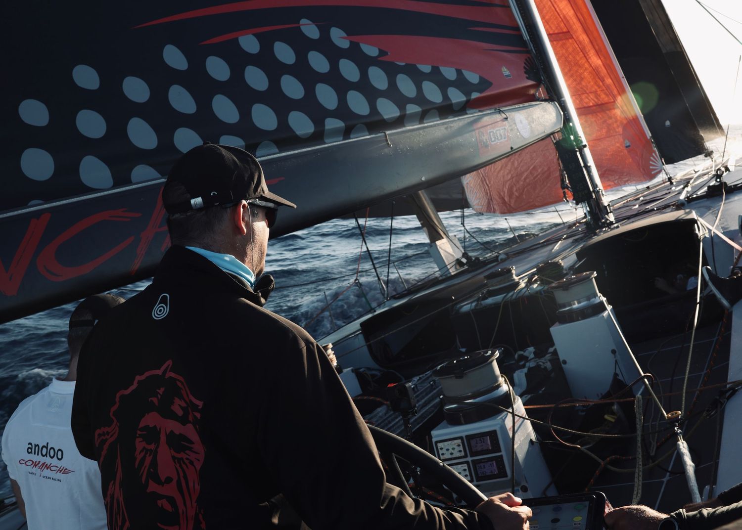 Racing yacht deck detail showing polka dot pattern on black sail with orange accents.