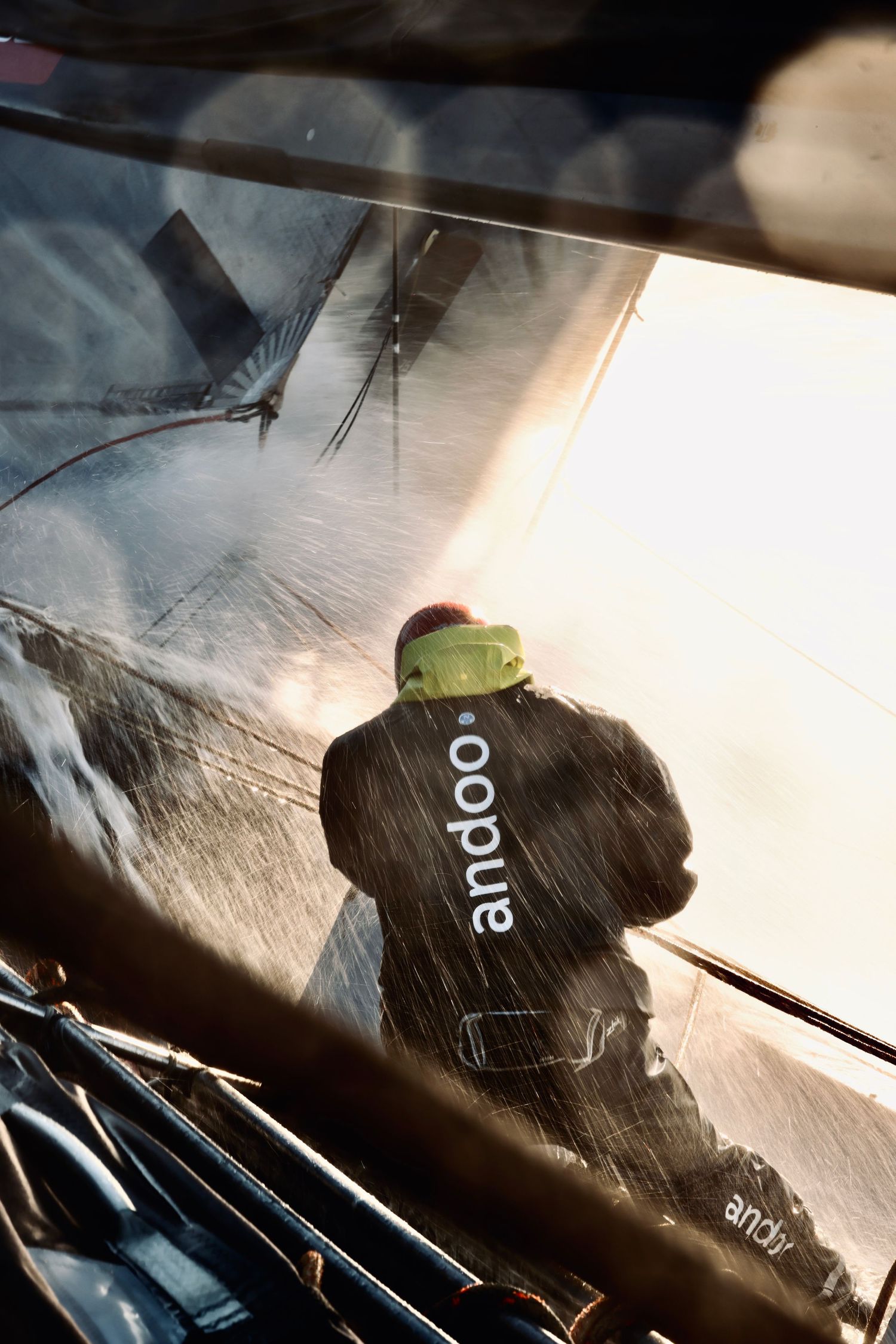 Racing crew in foul weather gear operating winches in stormy conditions.