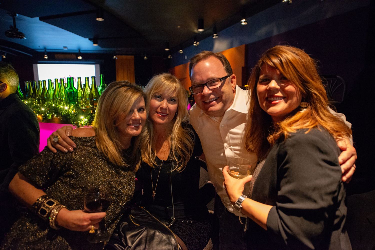 People hugging and embracing at a dimly lit party or social gathering.