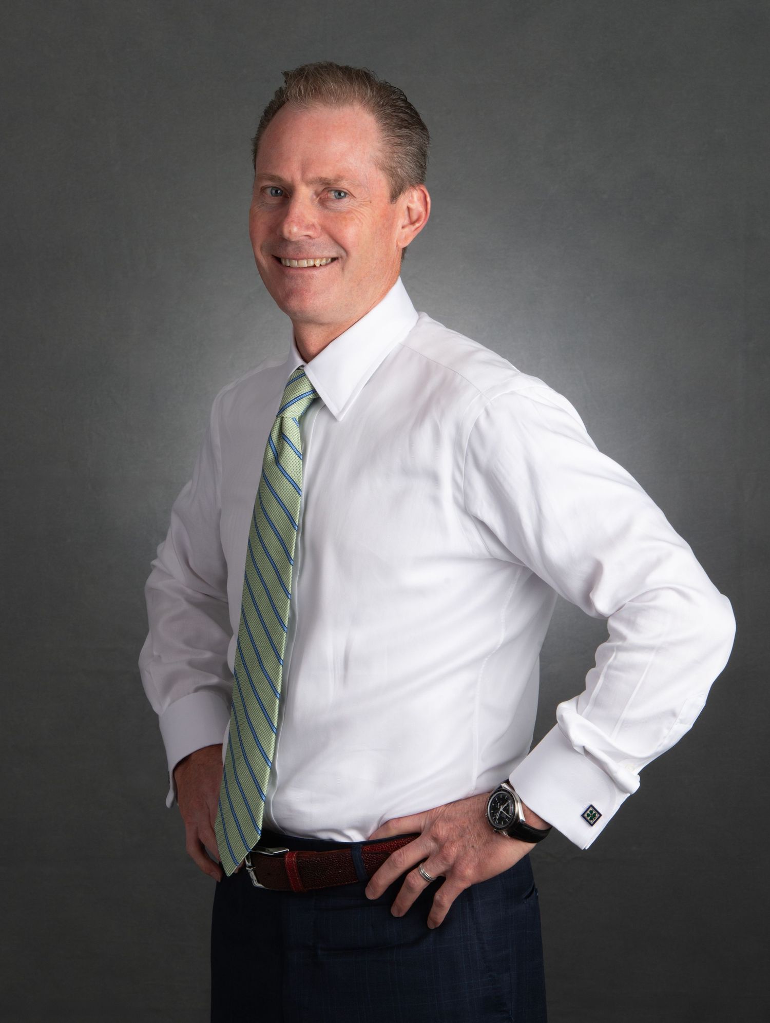 Denver Professional studio portraits show a person in business attire with a striped tie against a dark background.