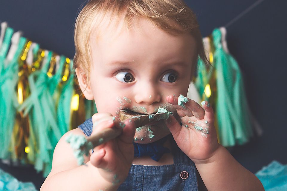 Close-up shots of a cake smash session with mint green frosting and teal tassels in the background.
