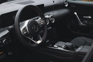Modern Mercedes-Benz interior featuring a black leather dashboard, steering wheel and digital displays in low light.