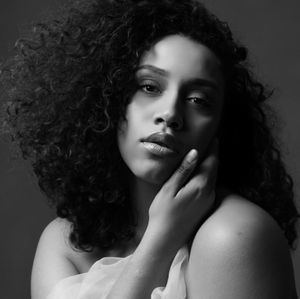 Artistic black and white portrait with dramatic shadows and natural curly hair.