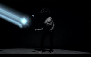 A dark silhouette of a person performing a dance move against a moonlit sky with dramatic lighting.