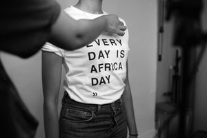 Person wearing a white graphic t-shirt with text that reads "AFRICA" paired with dark pants in black and white photo.