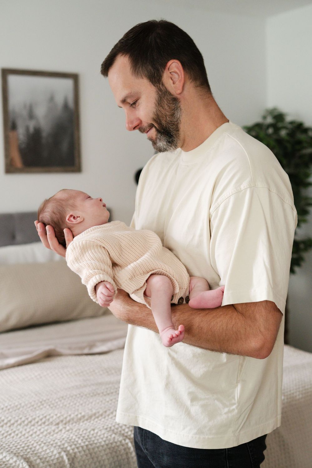 A parent holds and plays with their baby in a series of tender moments against a bright white bedroom background.