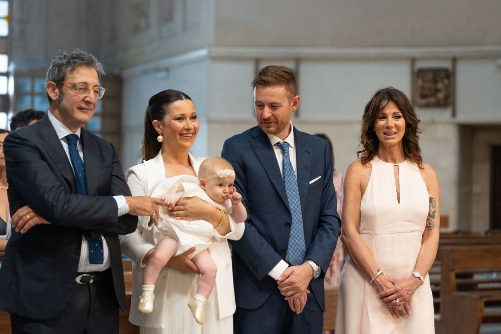 Group of people gathered for a formal religious ceremony wearing elegant attire in a church setting.