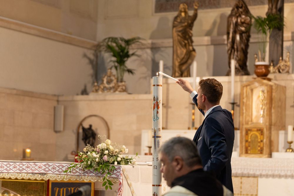 Religious baptism ceremony taking place inside a traditional church with ornate decorations.