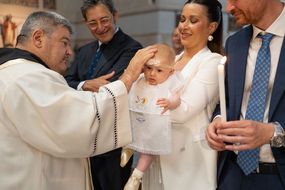 Group gathered around during baptism ceremony in church with white robes and formal attire.